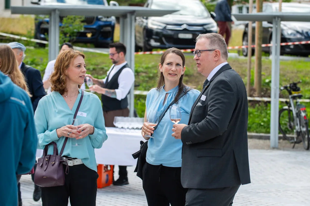 Mehrere Menschen stehen zusammen und reden und lachen. 